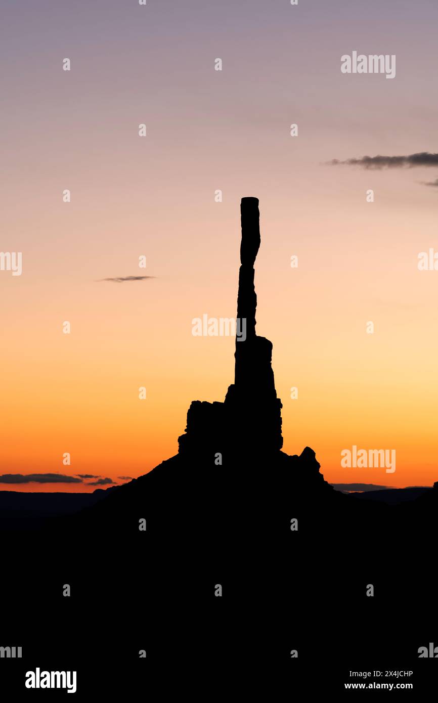 Sunrise behind Monument Valley's famous totem pole and nearby spires