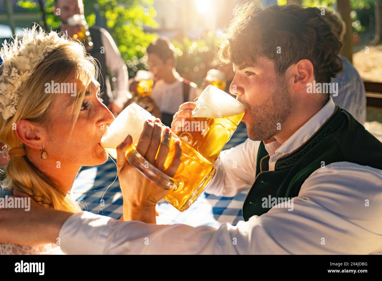 Intimate moment of a couple drinking beer in sunlight at Oktoberfest or beer garden, with a festive atmosphere in germany Stock Photo