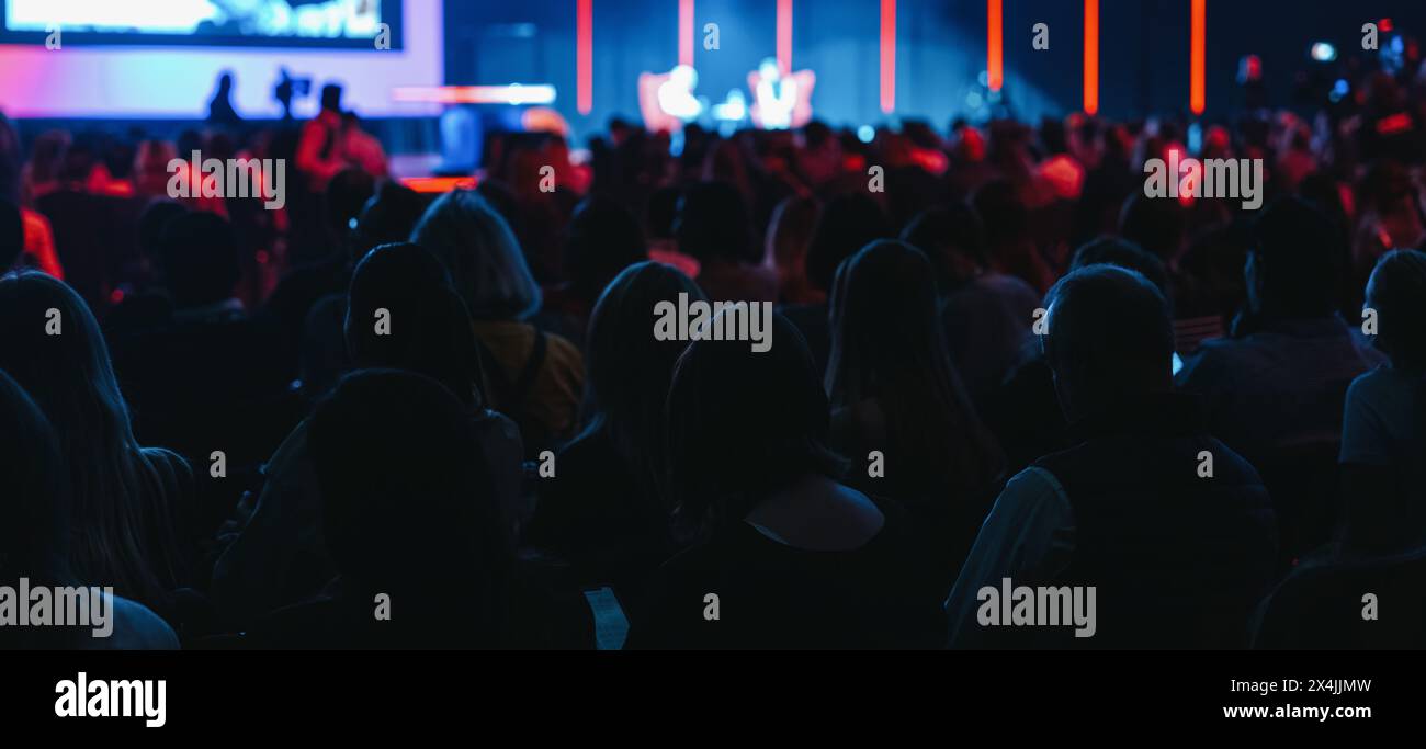 Audience watching a stage with colorful lighting at an event Stock Photo
