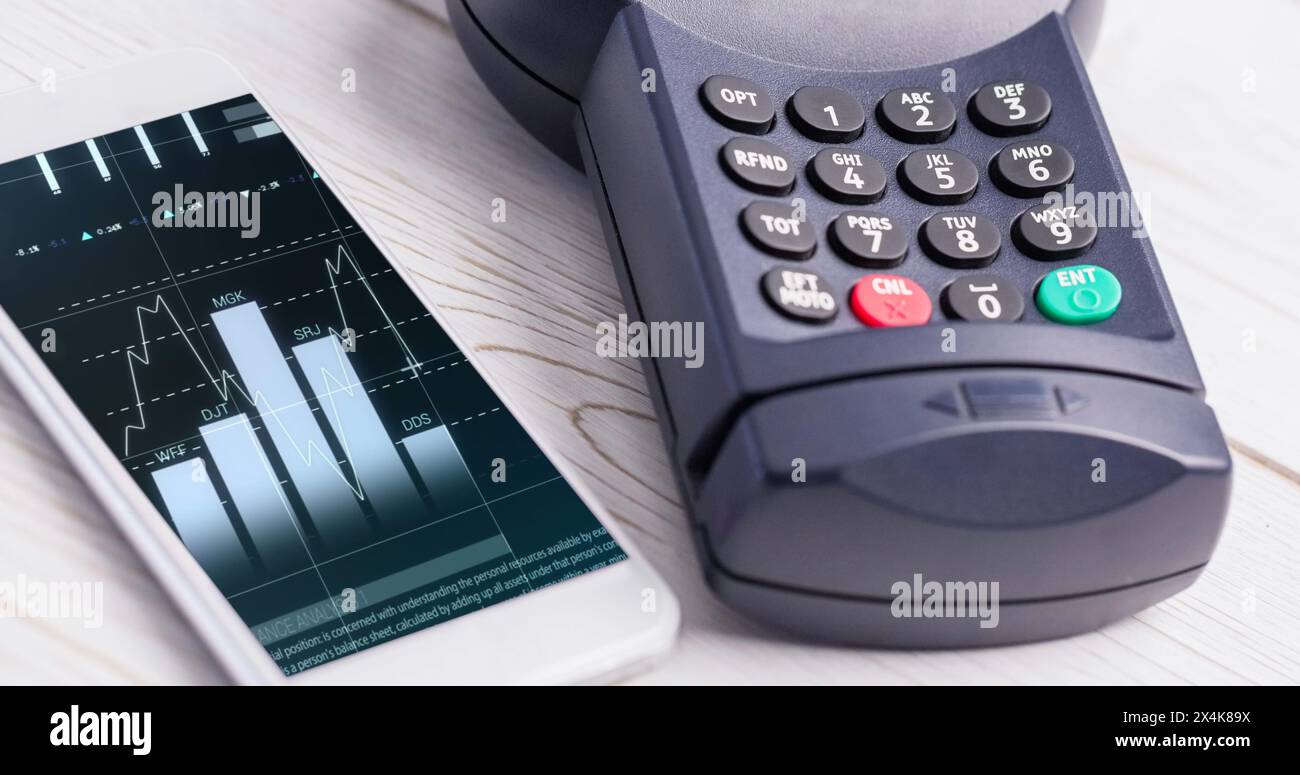 Image of financial data processing on smartphone next to credit card terminala. global finances, business and contactless payment concept digitally ge Stock Photo