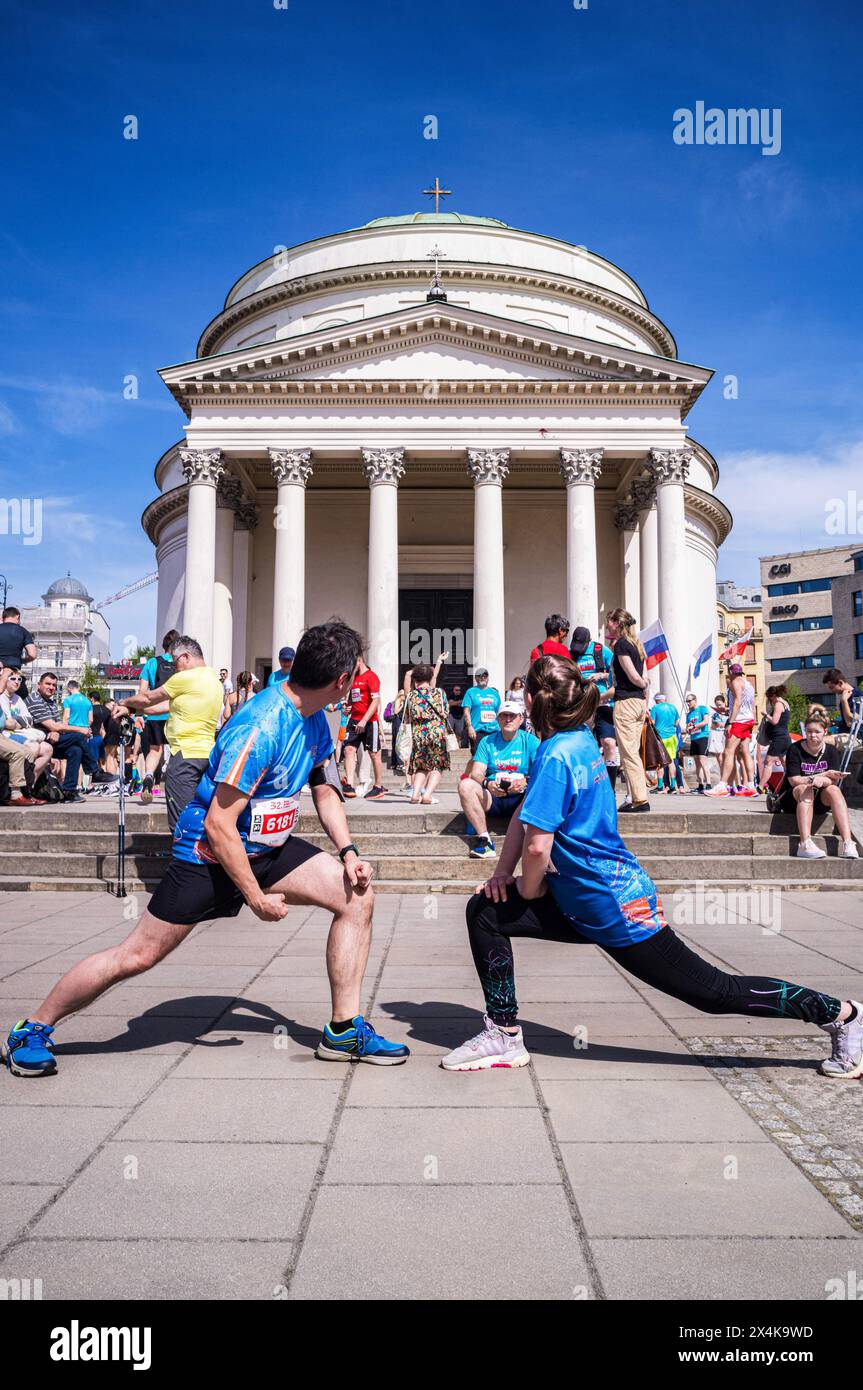 Two runners from the PKP Intercity railway running team warm up in front of St. Alexander's Church. On May 3rd, Poland's Constitution Day, over 5000 runners from across Poland gather to compete or participate in a 5km race in celebration of the country's written constitution. In Warsaw's beautiful place Trzech Krzy?y (Three Crosses Square), serious athletes, enthusiastic amateurs, and family groups enjoy the patriotic atmosphere in the springtime sunshine as they commemorate the signing of Poland's 1st constitution, penned on 3rd May 1791. (Photo by Neil Milton/SOPA Images/Sipa USA) Stock Photo