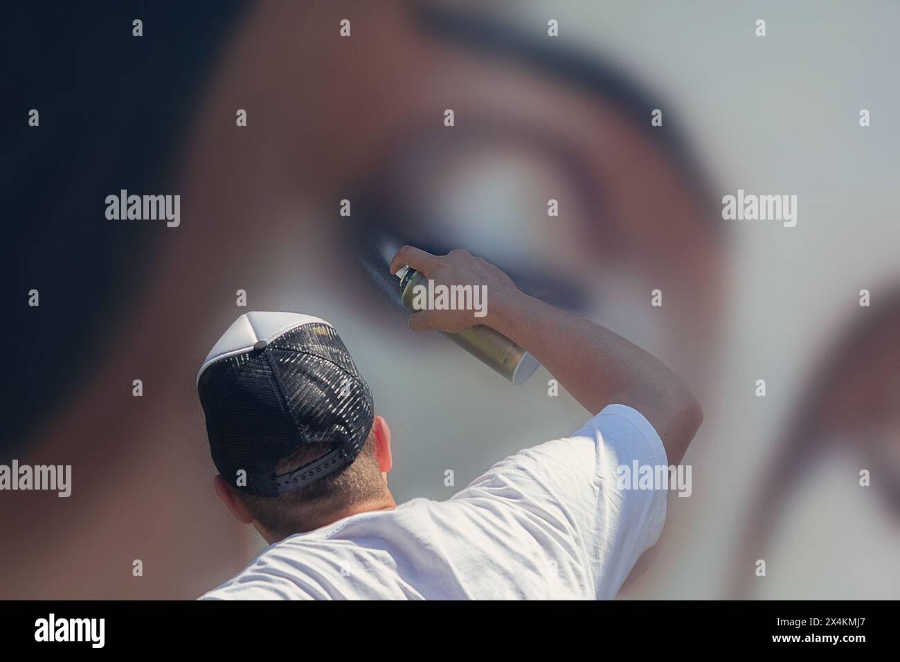 A man with a spray paint paints graffiti on the wall Stock Photo - Alamy