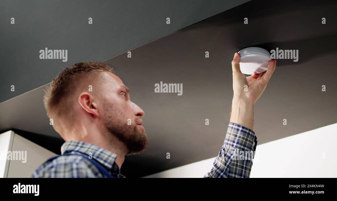 Installing Smoke Detector On Ceiling At Home Stock Photo