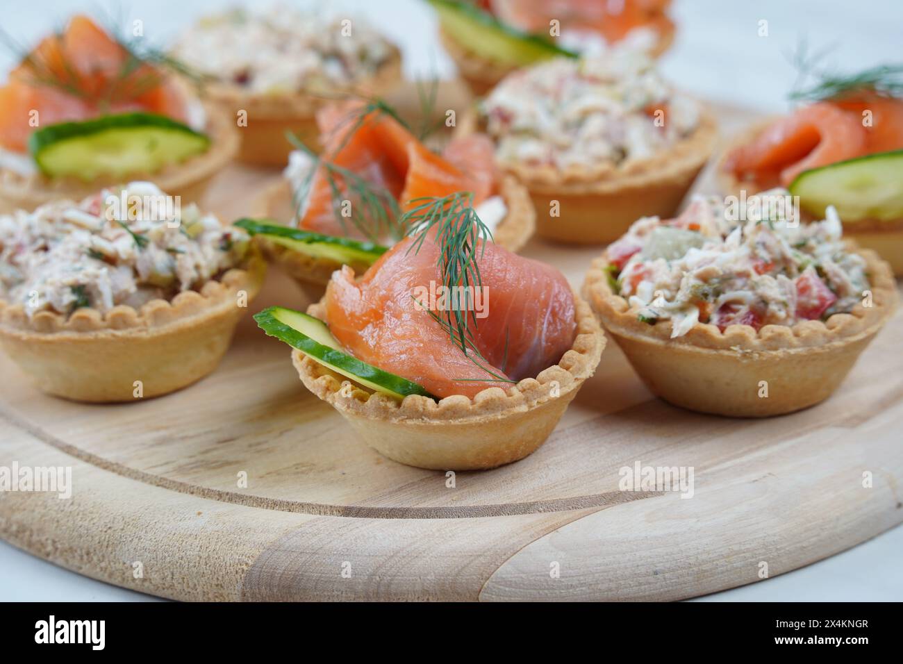 Tartlets with salmon, tuna, cheese, cucumber and dill. Tasty snacks with salted salmon and tuna filling Stock Photo