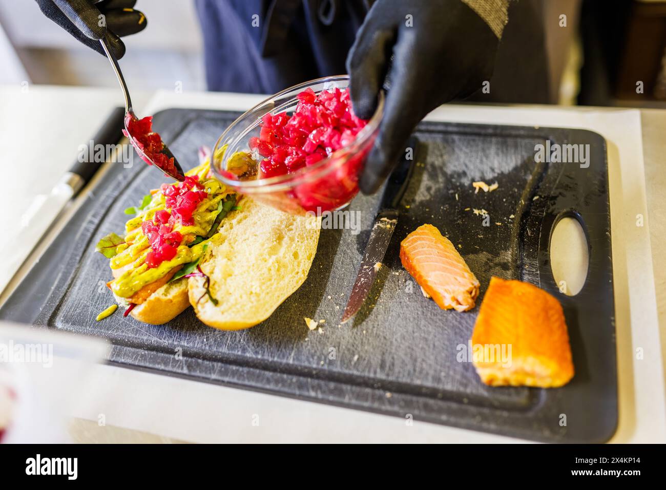 Freiamt, Germany. 04th May, 2024. Michael Wickert makes a fish roll with smoked salmon on today's World Fish Roll Day. The fish roll started with a simple Bismarck herring between two halves of the roll. Since then, matjes, fried herring, rollmops, salmon, mackerel, fried fish fillets and fish cakes have also found their way into the fish roll. Wickert runs the fish smokehouse 'Glut & Späne' in Freiamt, Baden. Credit: Philipp von Ditfurth/dpa/Alamy Live News Stock Photo