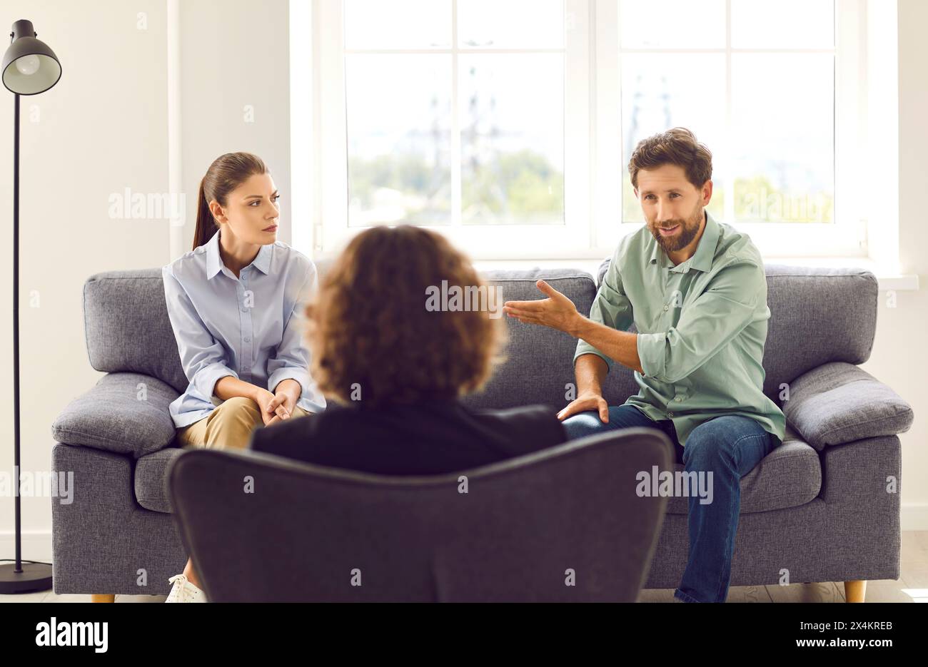 Young couple blaming each other in marriage problems sitting at family therapist office. Stock Photo