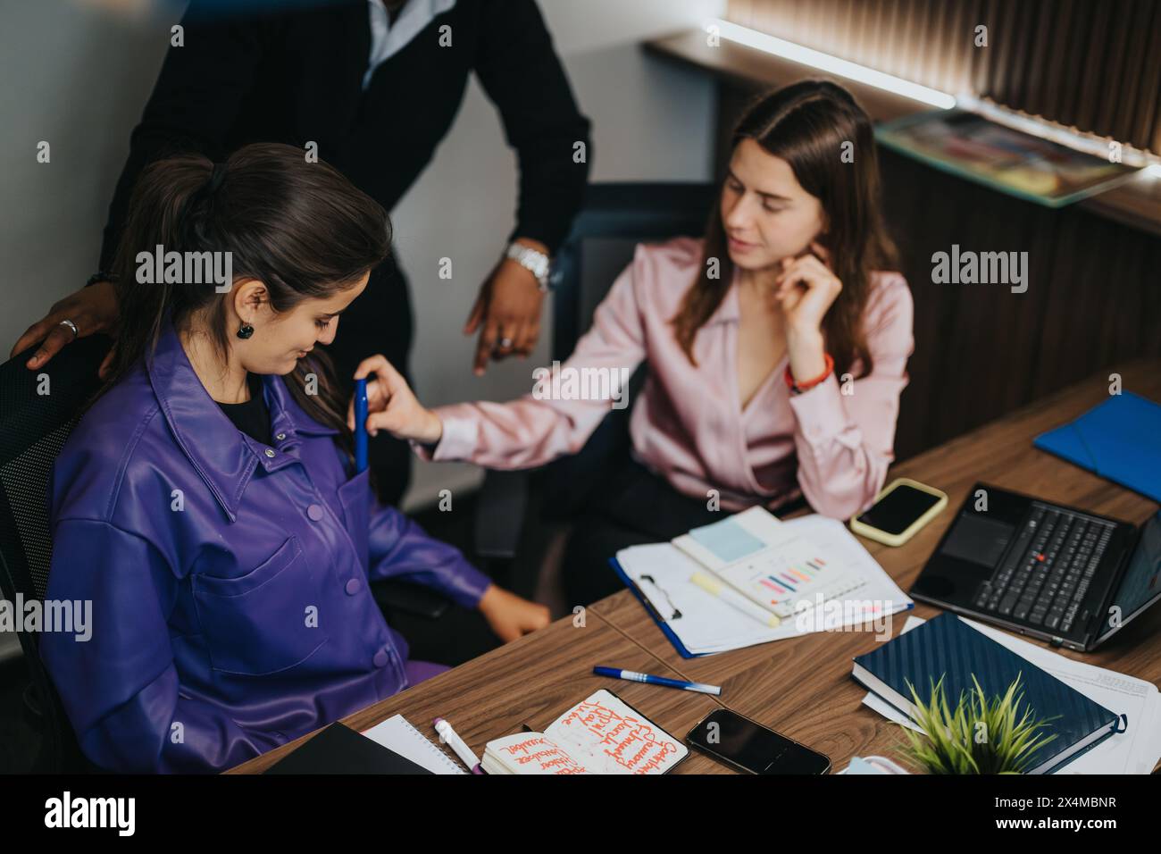 Business colleagues collaboratively analyzing project data in a modern office setting Stock Photo