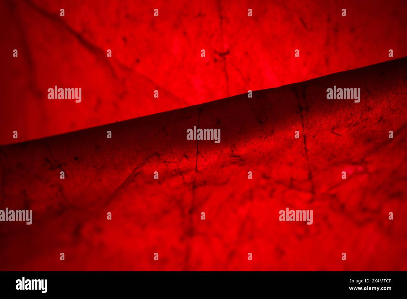 Extreme close up of red empty plastic bag background. The plastic surface is wrinkly and tattered making abstract pattern. Selective focus, shallow de Stock Photo