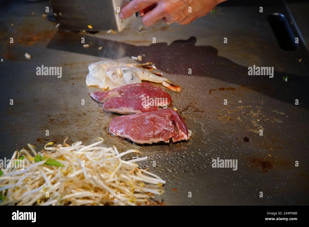 chef's hands with spatula over teppanyaki. cooking vegetables meat and