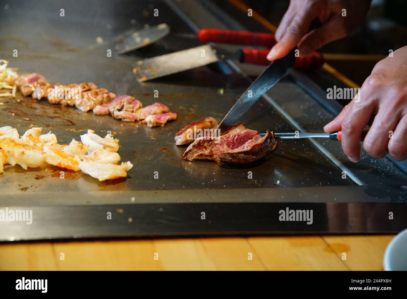 chef's hands with spatula over teppanyaki. cooking vegetables meat and
