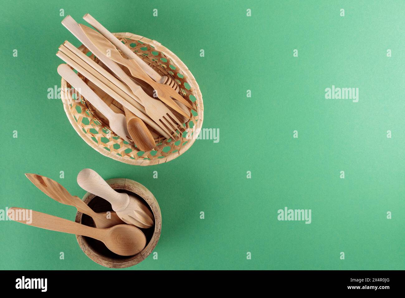 Wooden Kitchen Utensils Collection in Wicker Basket on Green Background, Top View, Copy Space Stock Photo