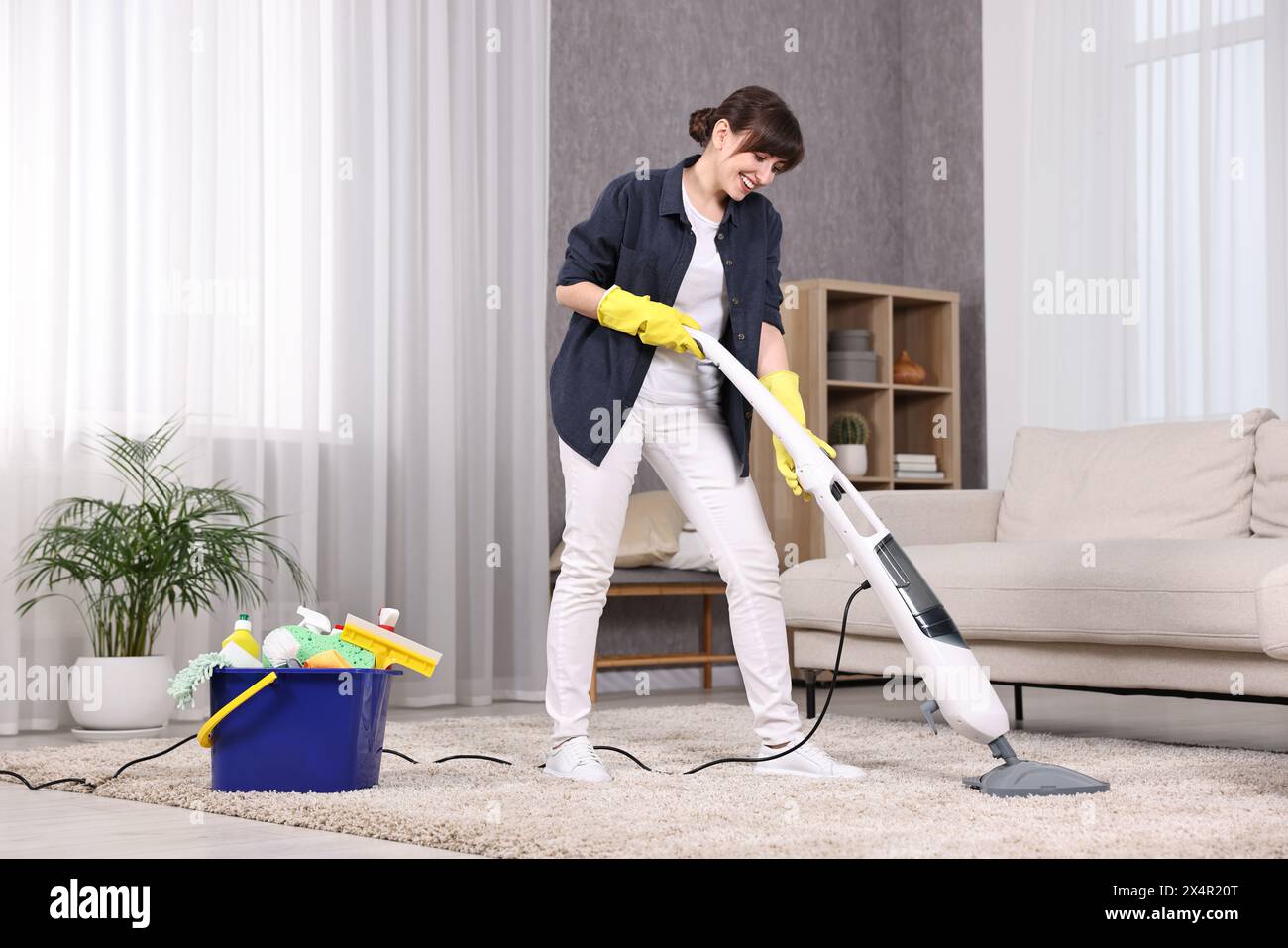 Happy young housewife vacuuming carpet at home Stock Photo - Alamy