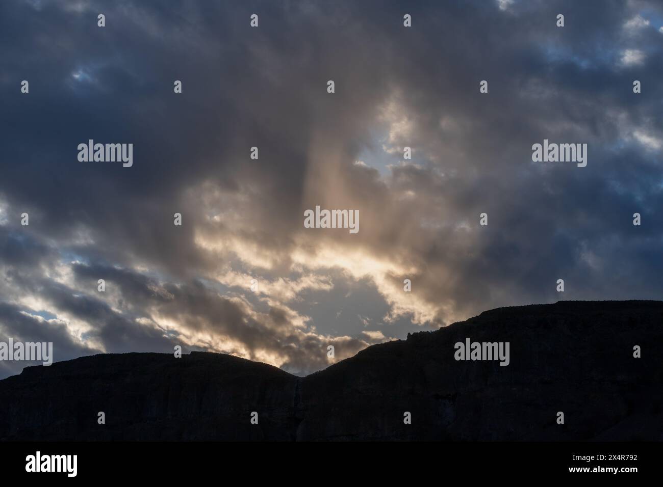 Dramatic Sun Rays Burst through the storm clouds at sunset Stock Photo