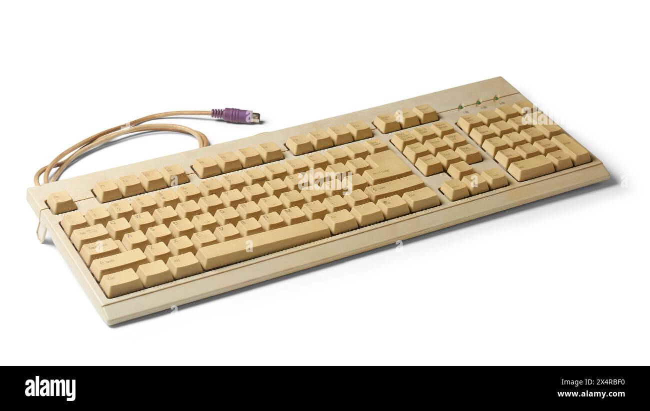 old used computer keyboard with ps/2 connector or port, beige color early days mechanical computer input device, isolated white background with shadow Stock Photo