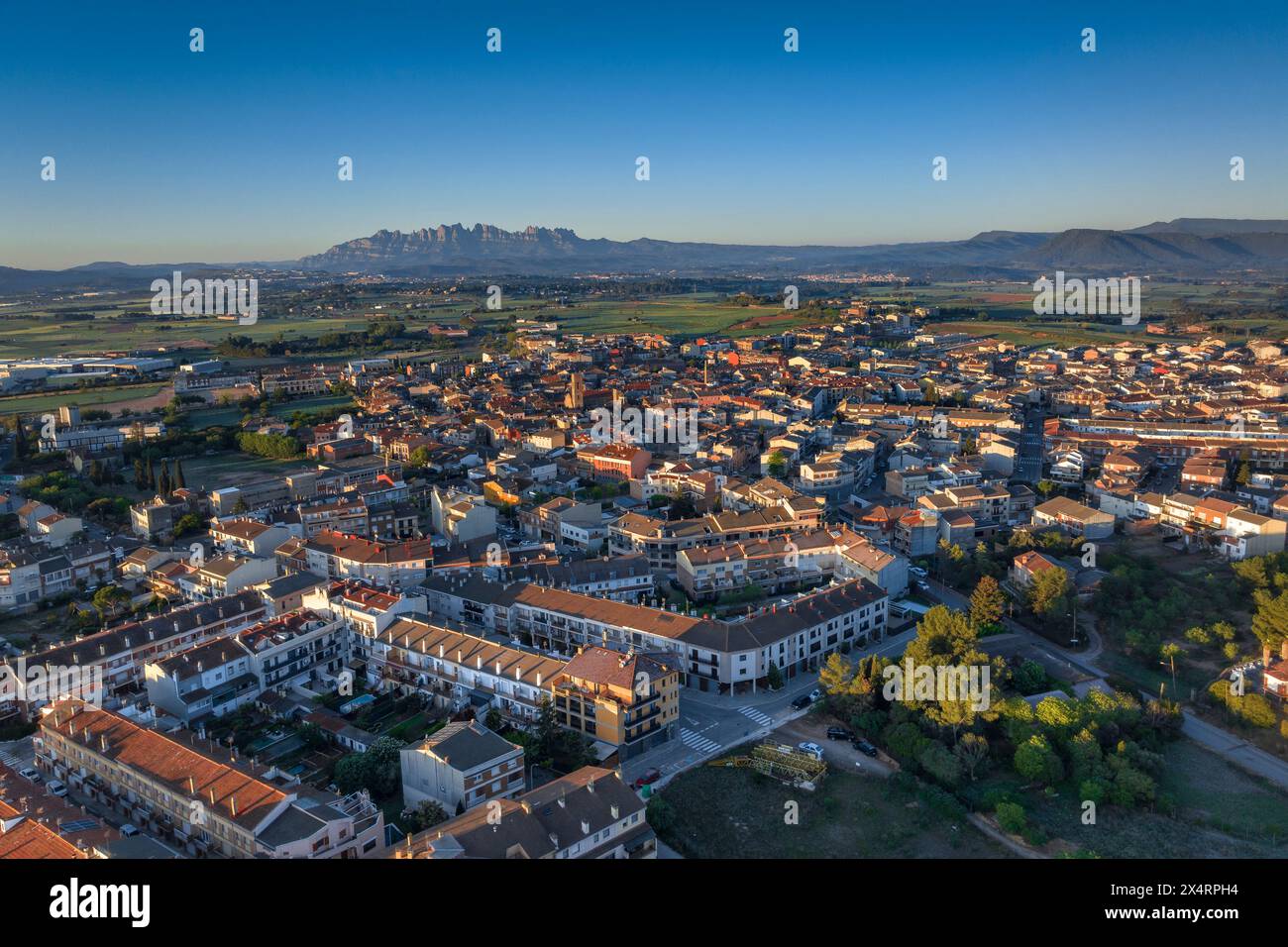 Aerial view of the town of Santpedor on a spring sunrise. In the background, the Montserrat mountain (Bages, Barcelona, Catalonia, Spain) Stock Photo