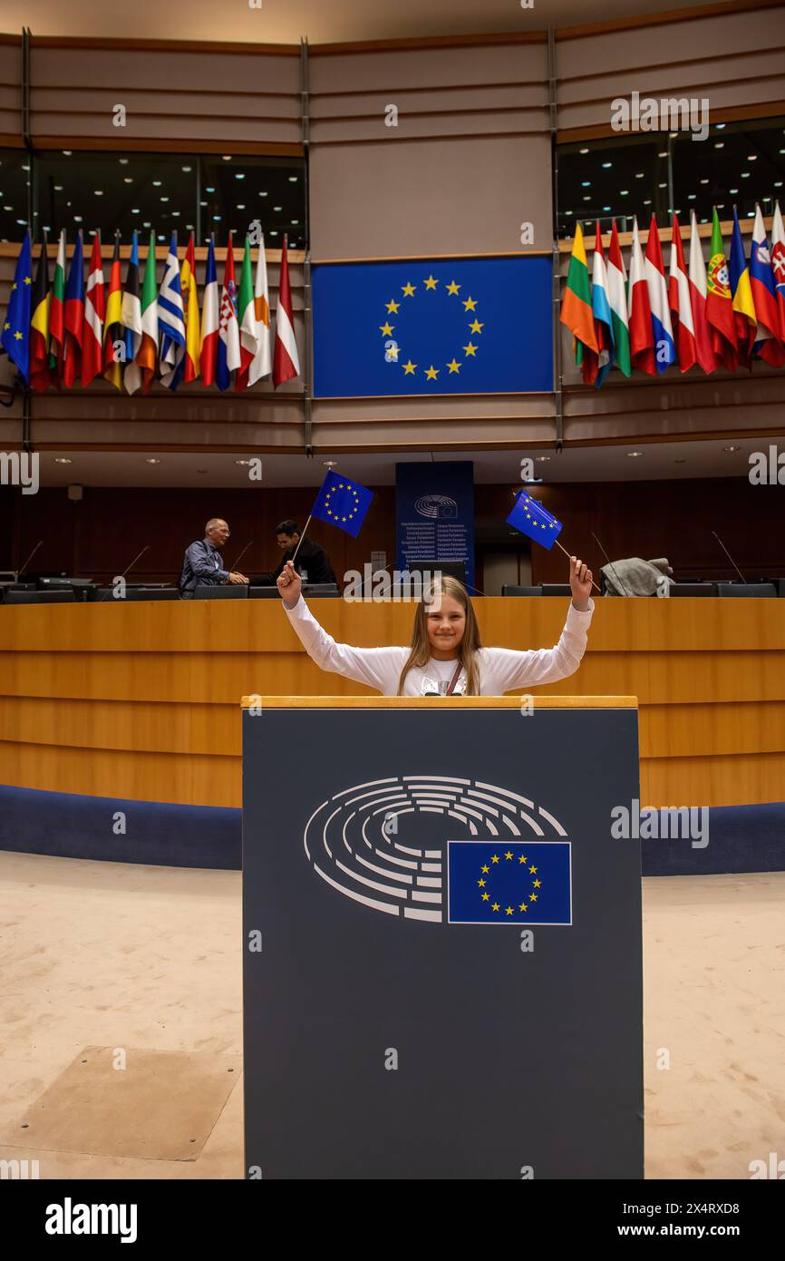 Young Julia from Poland stands at the podium of the EU Parliament during an open day to celebrate the birthday of the European Parliament in Brussels. Celebrating the European Parliament's birthday in Brussels, visitors gained special access to the Parliament chambers and the iconic building itself. The open day featured informative stands on the upcoming European Parliament elections, fostering political engagement and dialogue. Against the backdrop of European democracy, attendees immersed themselves in the legislative process, symbolizing transparency and civic participation. The event sho Stock Photo