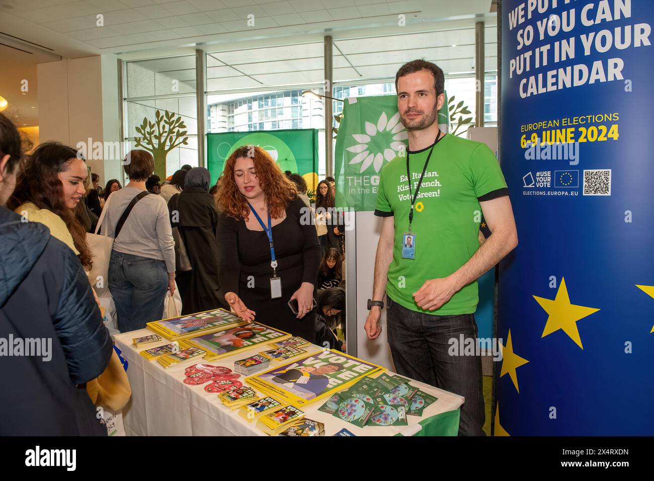 Party workers for the European Greens hand out stickers and information during an open day to celebrate the birthday of the European Parliament in Brussels. Celebrating the European Parliament's birthday in Brussels, visitors gained special access to the Parliament chambers and the iconic building itself. The open day featured informative stands on the upcoming European Parliament elections, fostering political engagement and dialogue. Against the backdrop of European democracy, attendees immersed themselves in the legislative process, symbolizing transparency and civic participation. The eve Stock Photo