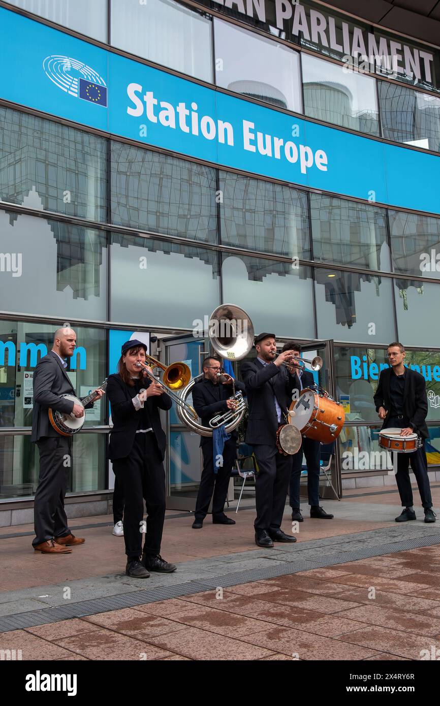 A band plays outside the Station Europe during an open day to celebrate the birthday of the European Parliament in Brussels. Celebrating the European Parliament's birthday in Brussels, visitors gained special access to the Parliament chambers and the iconic building itself. The open day featured informative stands on the upcoming European Parliament elections, fostering political engagement and dialogue. Against the backdrop of European democracy, attendees immersed themselves in the legislative process, symbolizing transparency and civic participation. The event showcased the diverse voices Stock Photo