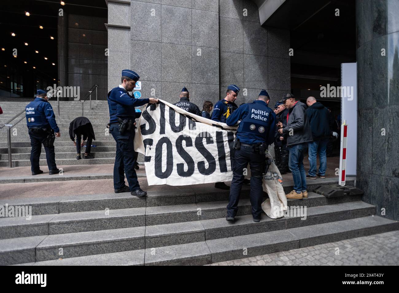 4th May 2024, Brussels, Belgium. Police inspect a banner reading 'Stop Funding Fossil Fuels' while detaining multiple young protesters outside the European Parliament on its public open day. The protesters were then handcuffed and taken away in an unmarked white van. Credit: Alamy Live News Stock Photo