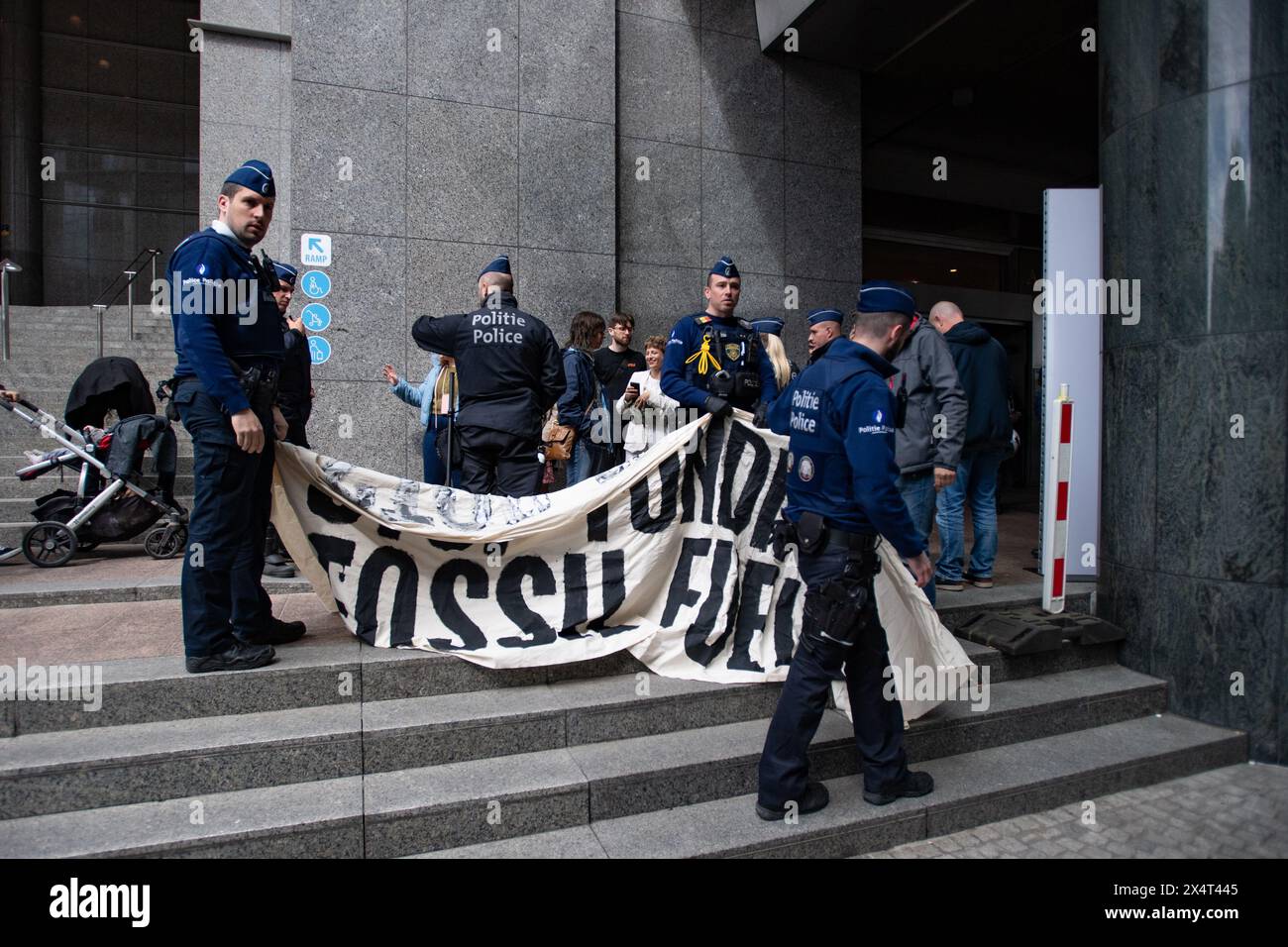 4th May 2024, Brussels, Belgium. Police inspect a banner reading 'Stop Funding Fossil Fuels' while detaining multiple young protesters outside the European Parliament on its public open day. The protesters were then handcuffed and taken away in an unmarked white van. Credit: Alamy Live News Stock Photo