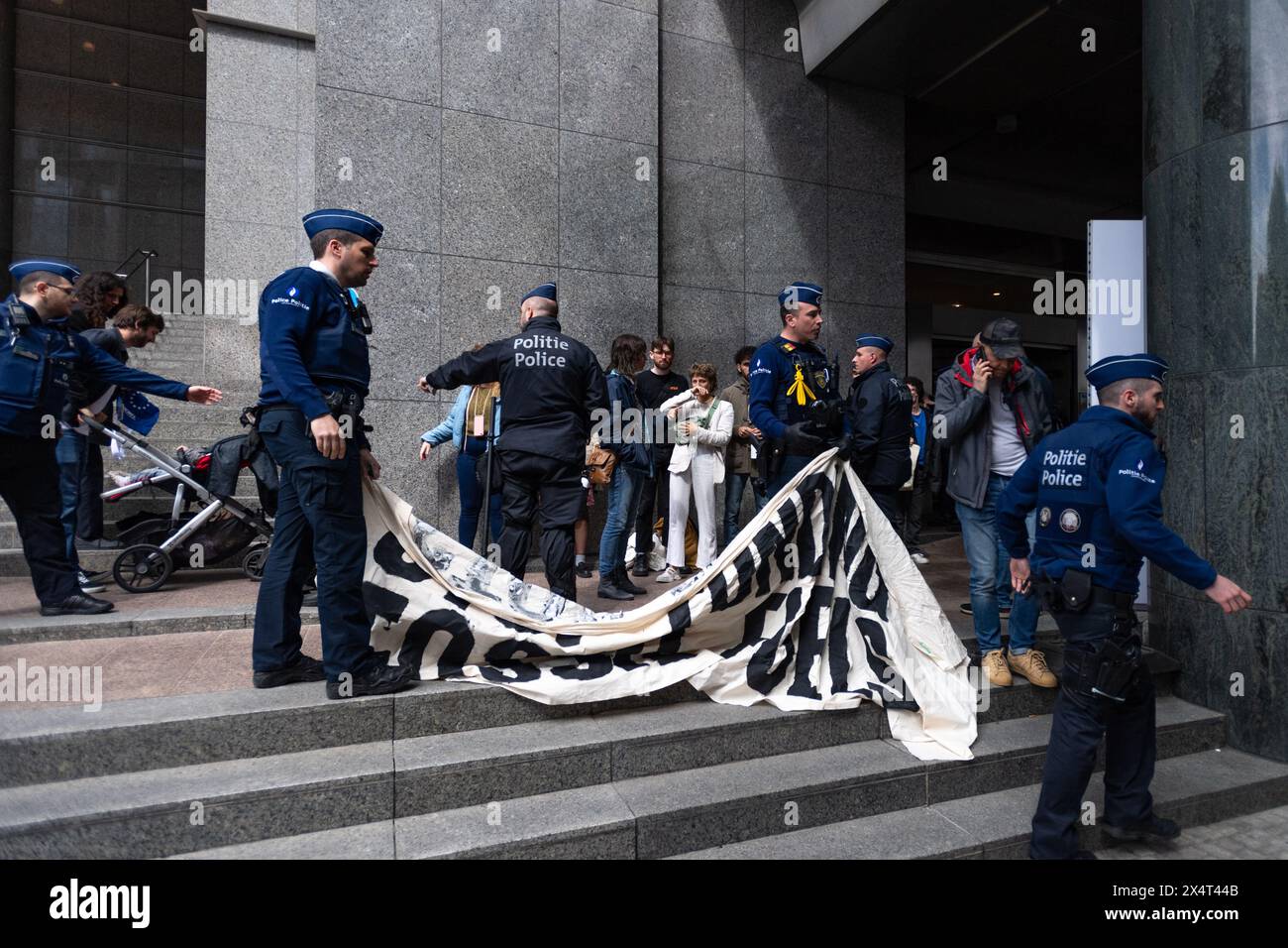 4th May 2024, Brussels, Belgium. Police inspect a banner reading 'Stop Funding Fossil Fuels' while detaining multiple young protesters outside the European Parliament on its public open day. The protesters were then handcuffed and taken away in an unmarked white van. Credit: Alamy Live News Stock Photo