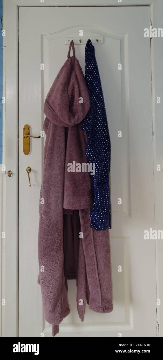 Isolated bathroom door with bathrobe and pyjamas hanging on it Stock Photo