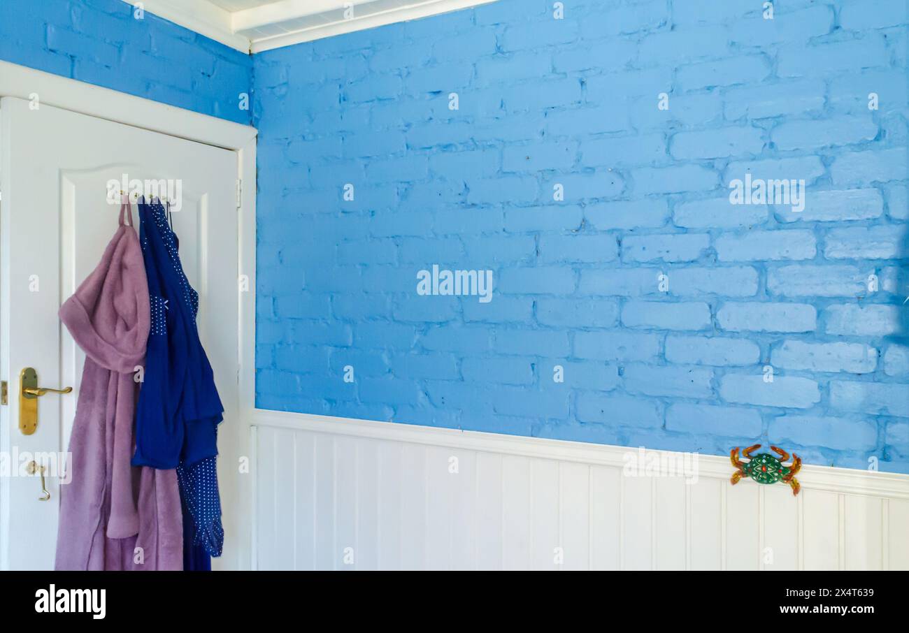 Bathroom door with bath robe and a pair of pyjamas hanging and a blue brick wall Stock Photo