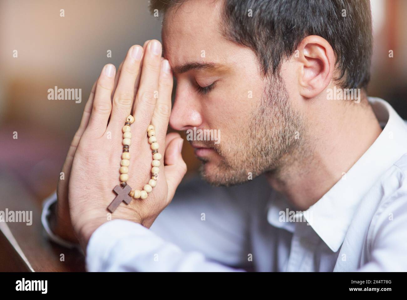 Man, praying and hands for closeup, church and crucifix cross with rosary, christian and religion. Worship, gratitude and belief or God, kneeling and Stock Photo