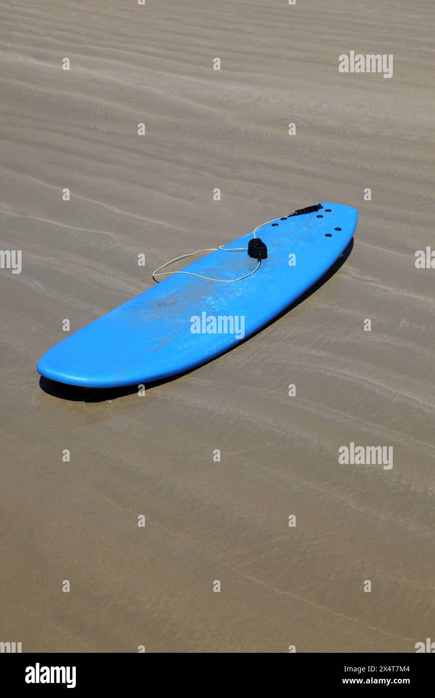 A soft blue malibu surfboard on the sand at the beach. Board such as these a perfect for learners to use and are commonly used in surf schools. Stock Photo