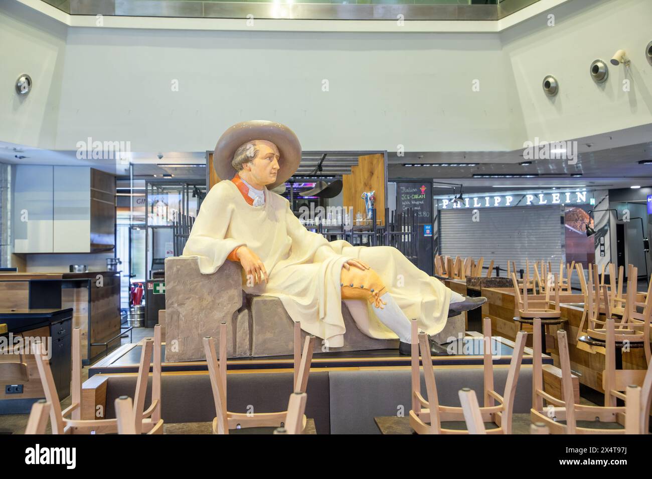 Frankfurt, Germany - April 26, 2024: statue of johann Wolfgang von Goethe in lying pose as in italian travel painting at a closed cafe at Frankfurt ai Stock Photo