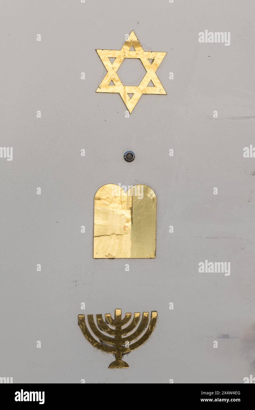 A white doorway in Jerusalem, Israel, decorated with three gold symbols of the Jewish faith: a six-pointed Star of David, tablets of the 10 commandmen Stock Photo