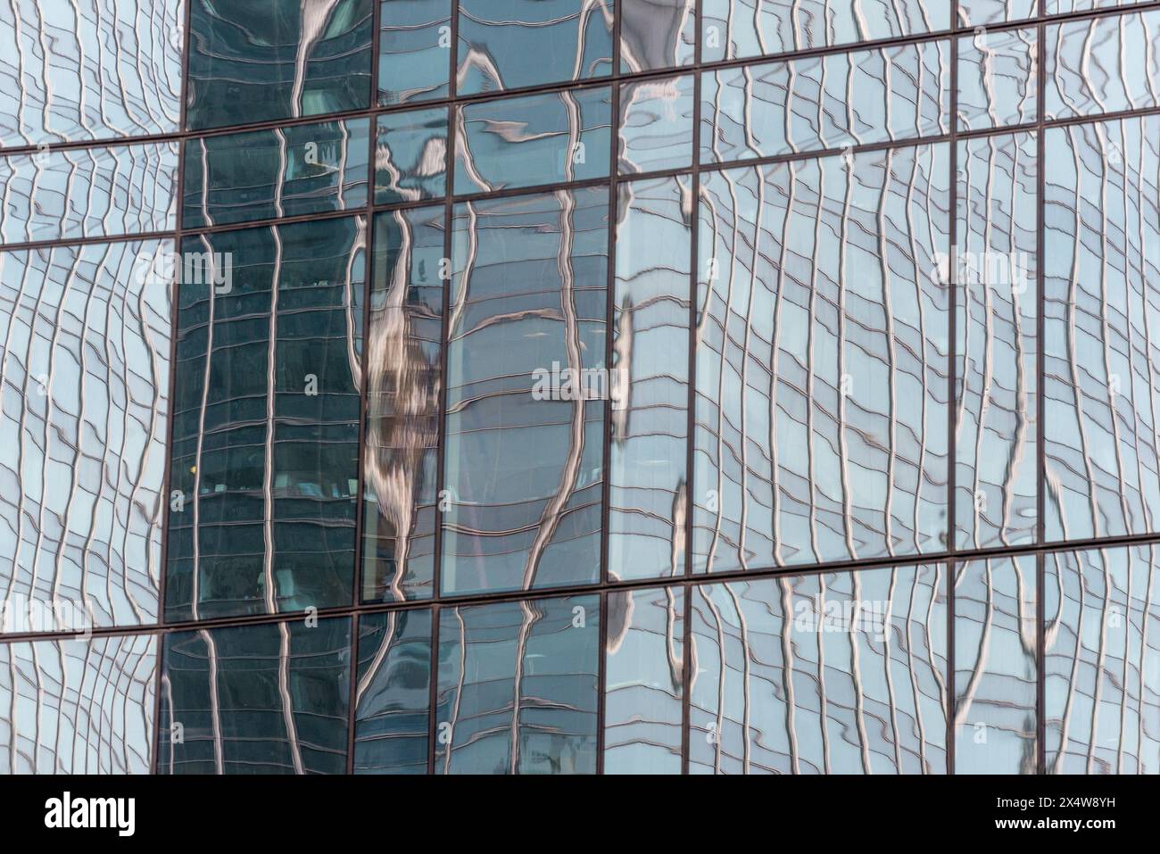 The reflection of a building in the glass window of a building. The reflection is distorted and wavy, giving the impression of a water surface Stock Photo