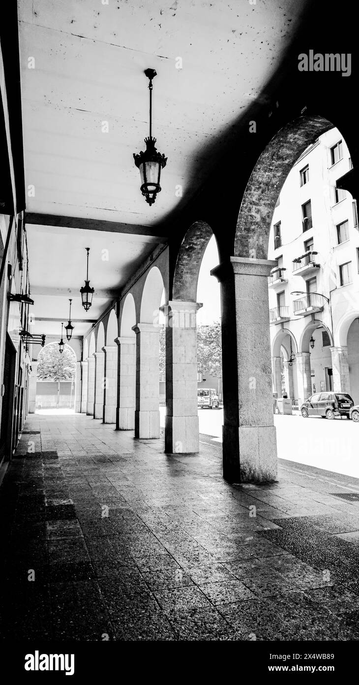 A traditional colonnade provides shade for pedestrians in the historic city of Girona, Spain Stock Photo