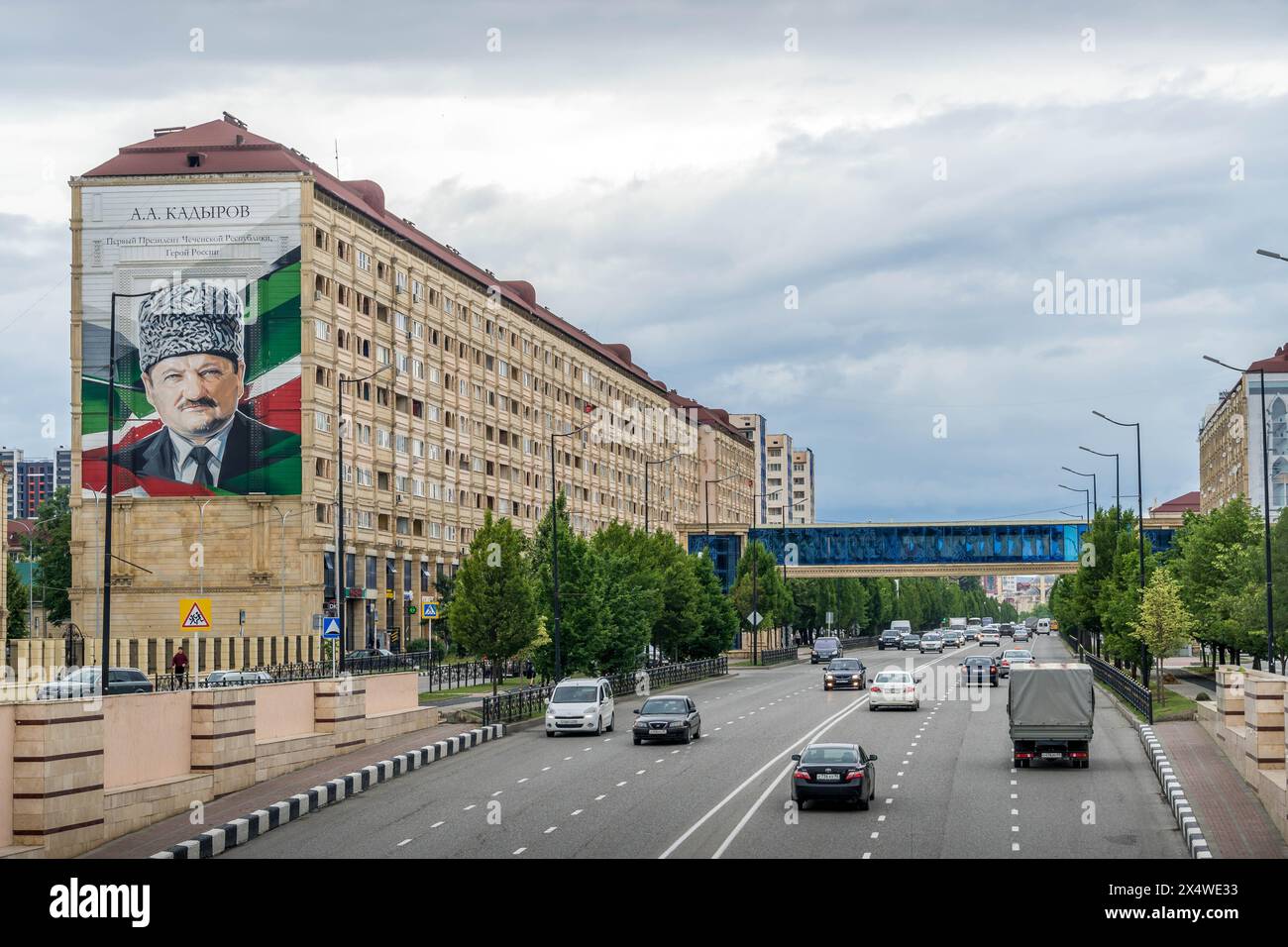 The traffic on the highway in Grozny city downtown, and the residential building with the giant portrait of Chechen Republic ex-president Akhmad Kadyr Stock Photo