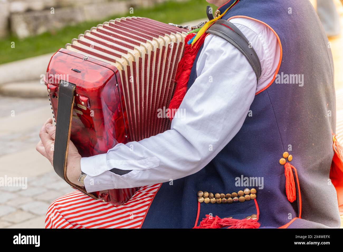 A street musician in traditional Krakow clothes plays the harmonium Stock Photo