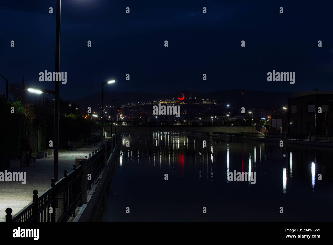Night Scene of a bridge constructed over a water channel and a red moon ...