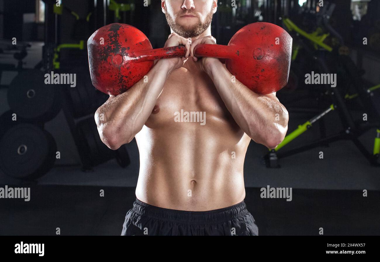 Muscular man lifts a heavy kettlebell during a workout in the gym. Sport concept, fat burning and healthy lifestyle. Stock Photo