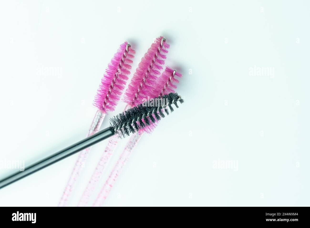 Top view of a Composition of four mascara applicators. Three pink and one black Stock Photo