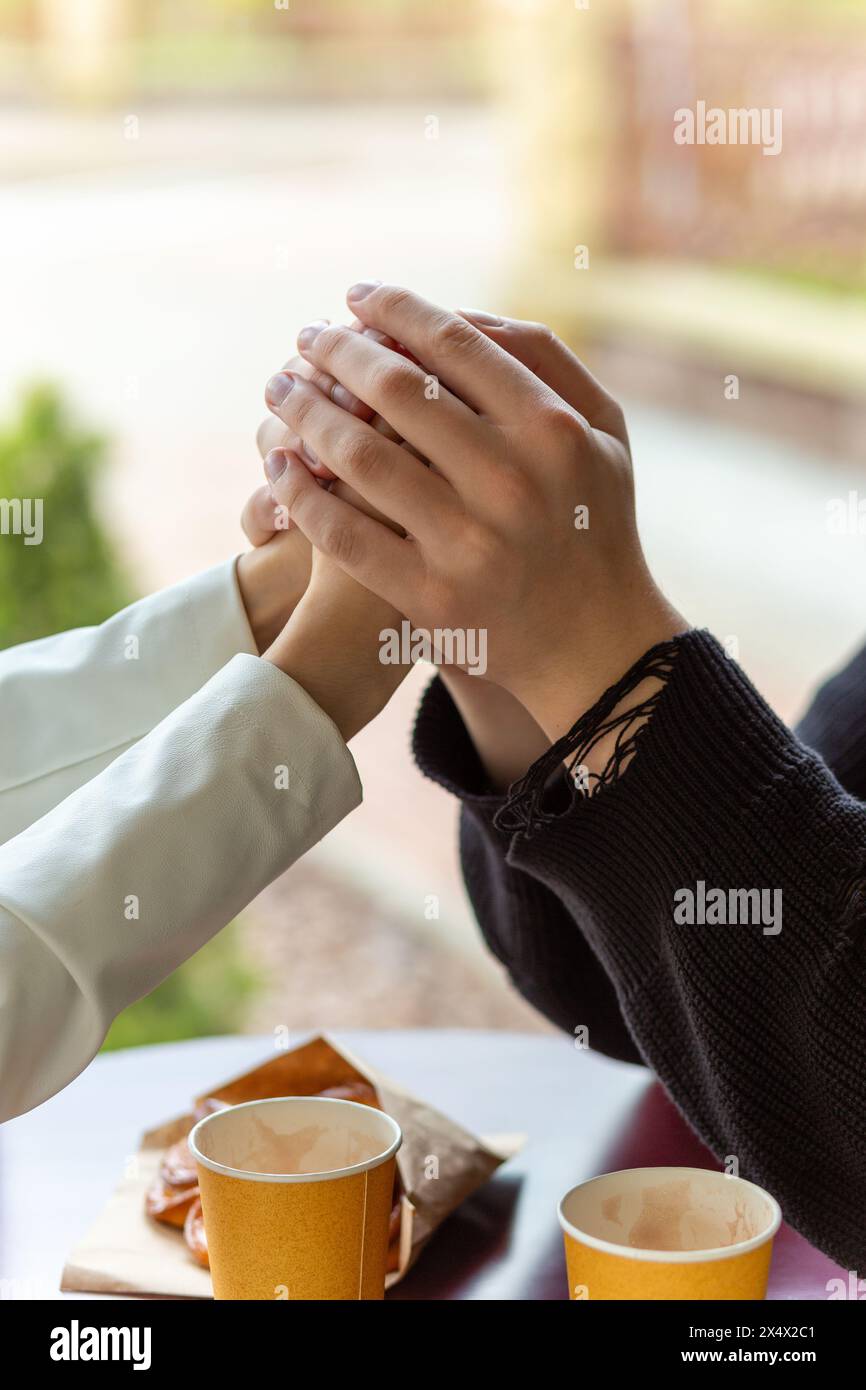 Couple enjoying a coffee holding hands. Holding hands, the hands of a couple who love each other. Bokeh portrait photo concept. Stock Photo