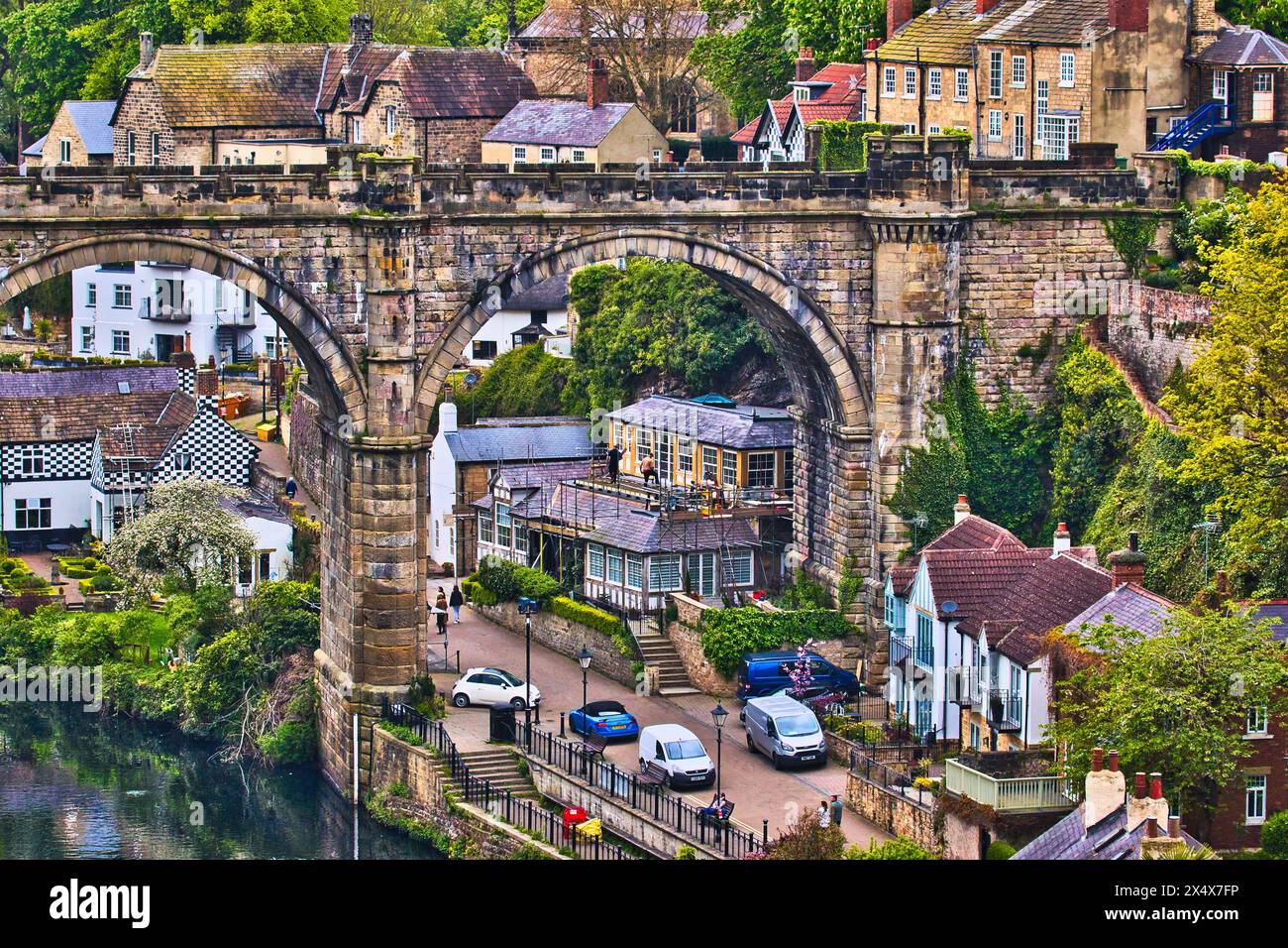 A picturesque view of a quaint village with an old stone bridge arching ...