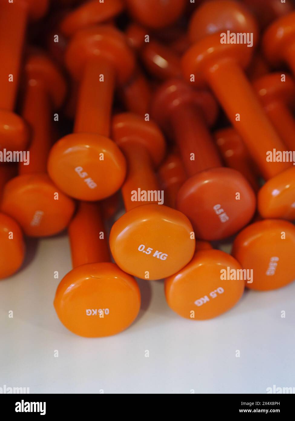 A stack of orange dumbbells with the numbers 0-5 kg on the top Stock Photo