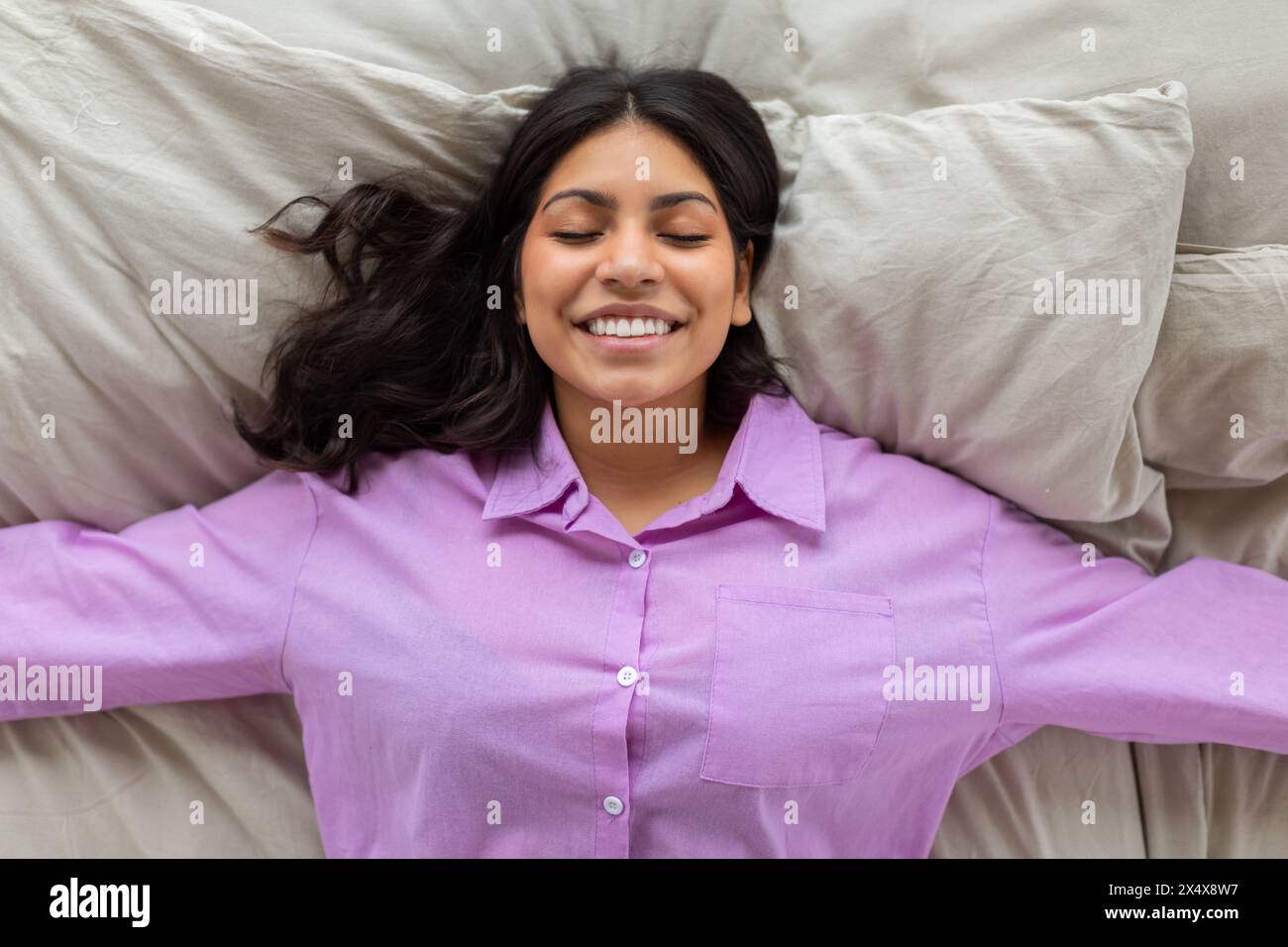 Woman Laying on Bed With Arms Outstretched Stock Photo