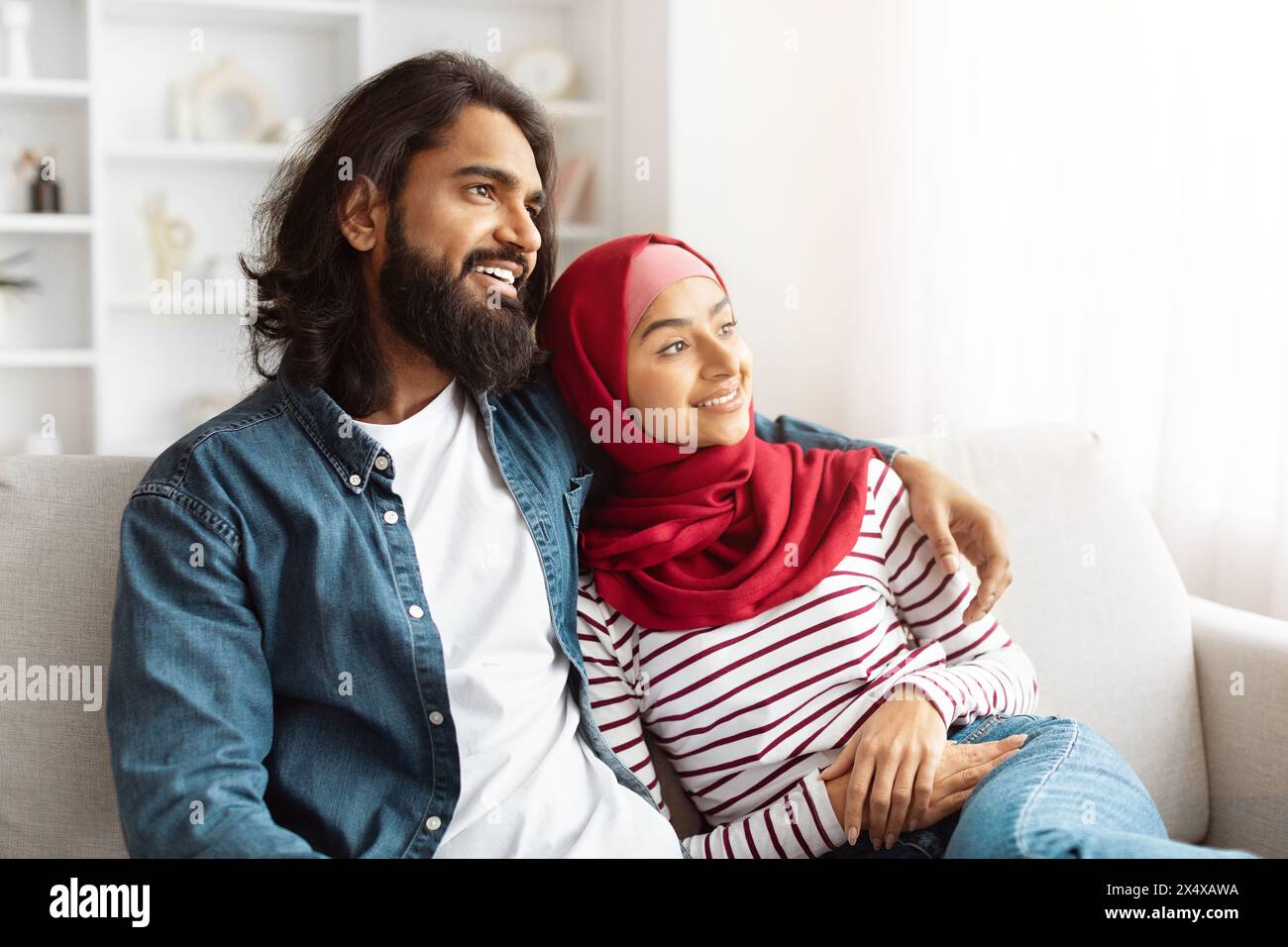 A Man and a Woman Sitting on a Couch, Hugging Stock Photo