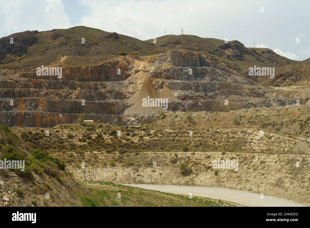 Overcast skies loom above a vast limestone quarry revealing stratified ...