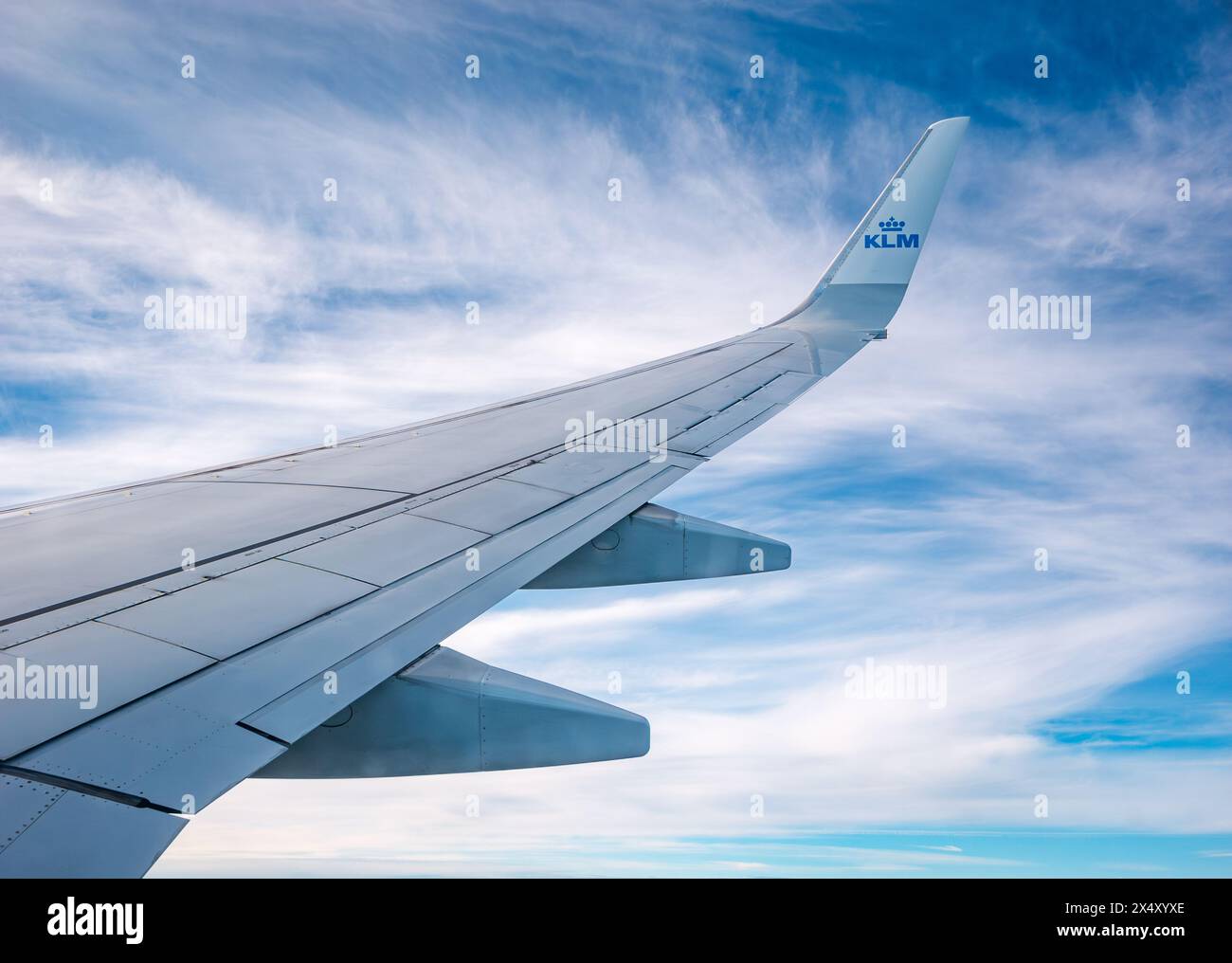 View from KLM plane window of airplane wing against wispy clouds and sky Stock Photo