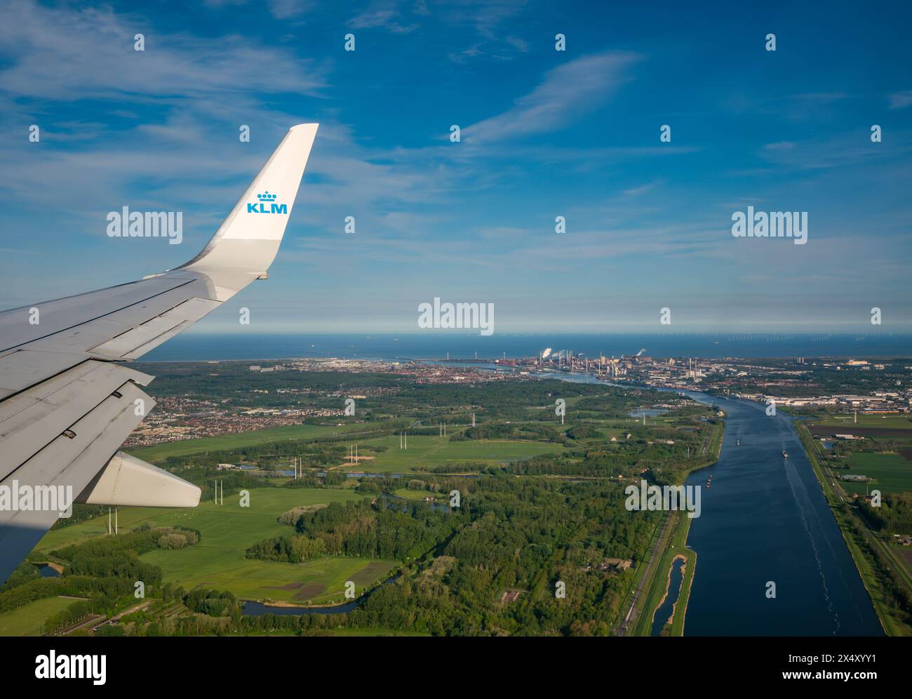 View from KLM plane window of airplane wing, canal from Ijmuiden and Tata steel works in the distance, Netherlands Stock Photo