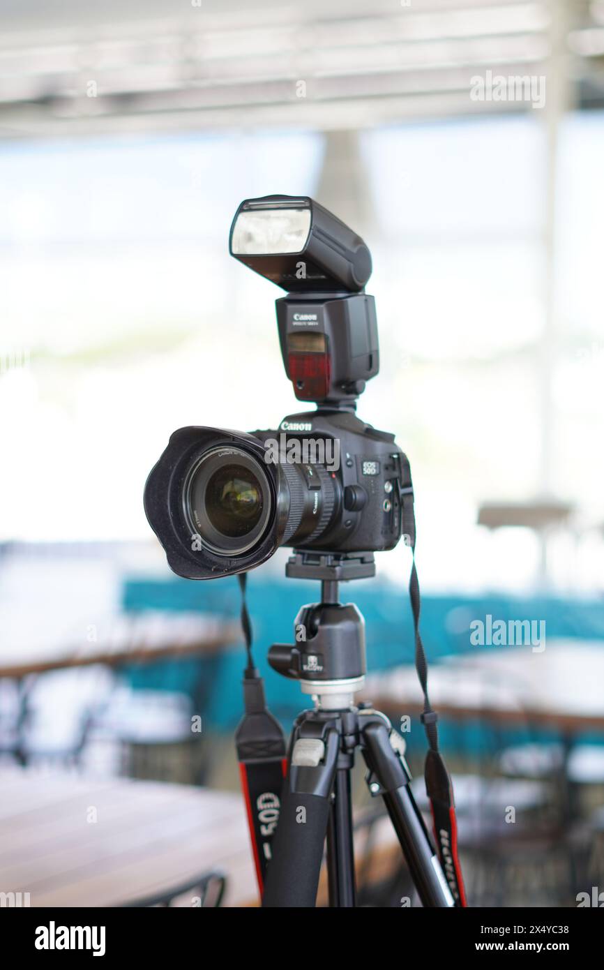 Black Canon DSLR camera mounted on a tripod with an external flash