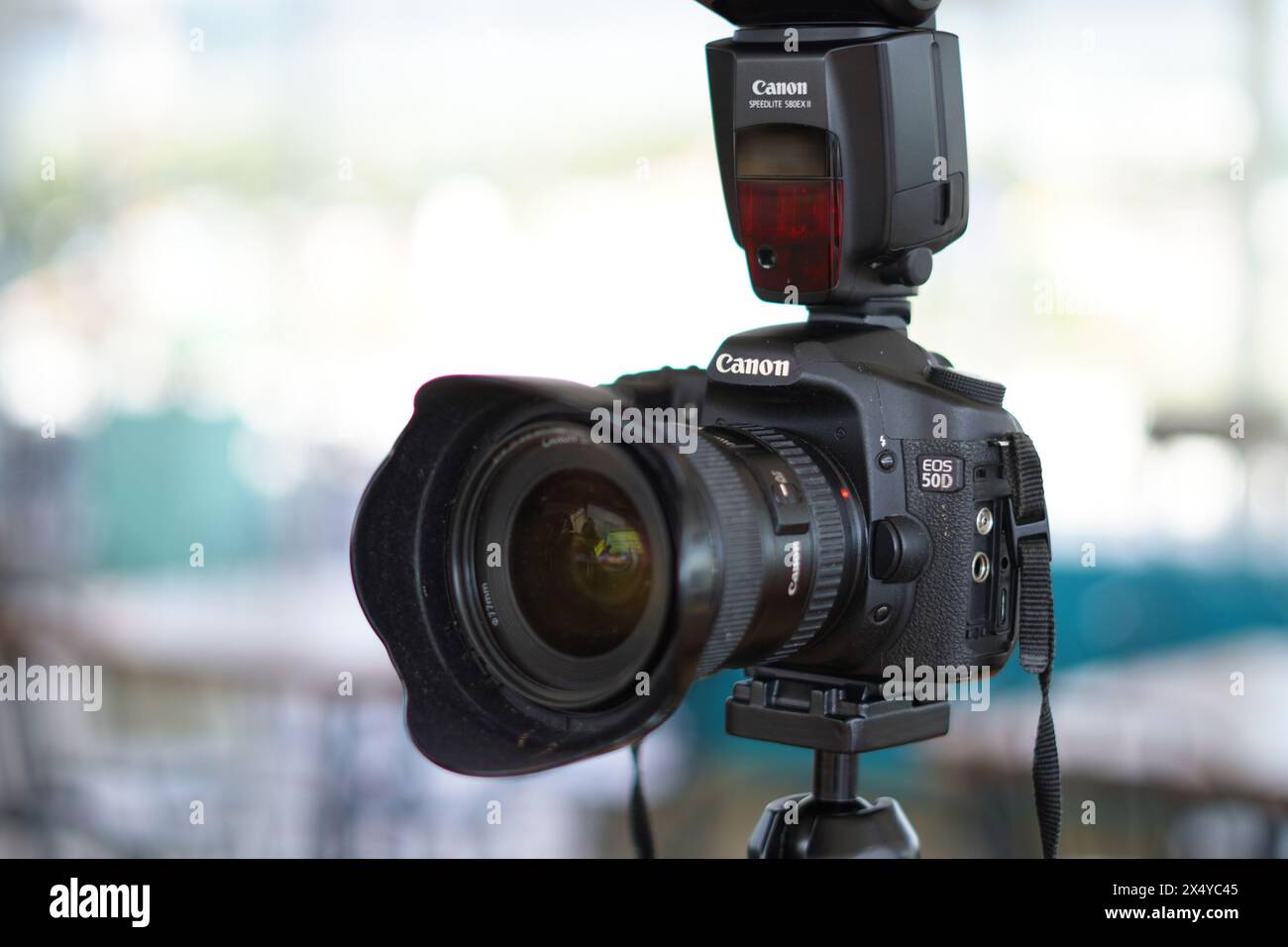 Black Canon DSLR camera mounted on a tripod with an external flash