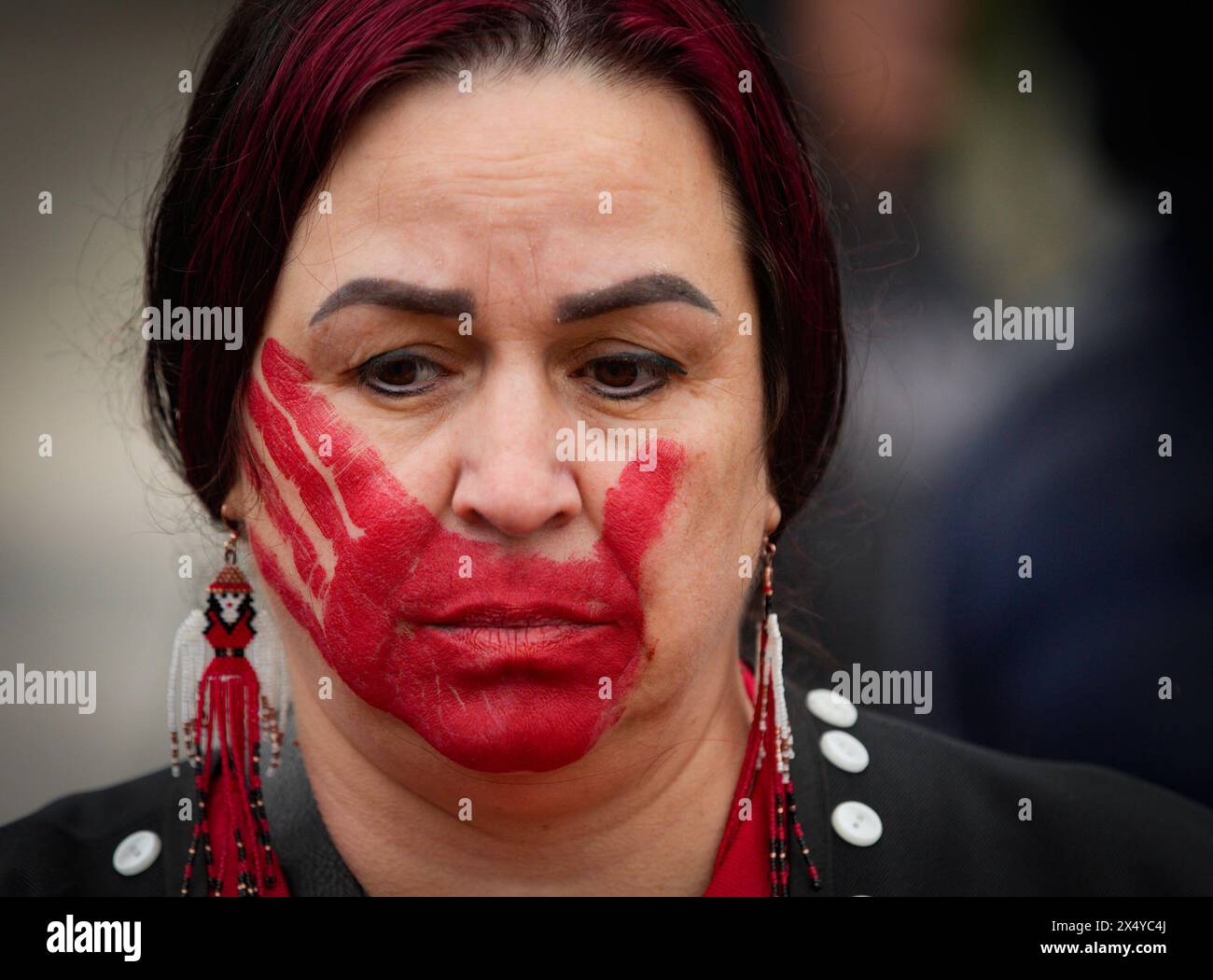 New Westminister, Canada. 5th May, 2024. An indigenous woman bearing hand-shaped paint mark over her mouth is seen during the Red Dress Day ceremony in New Westminster, British Columbia, Canada, on May 5, 2024. May 5 is the National Day of Awareness for Missing and Murdered Indigenous Women and Girls, also known as Red Dress Day, in Canada. Credit: Liang Sen/Xinhua/Alamy Live News Stock Photo