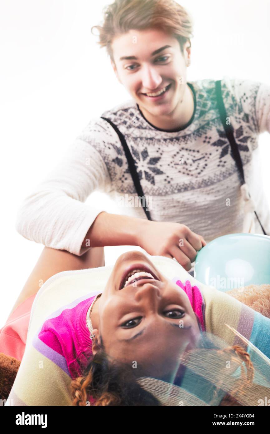 Playful scene with a young man and woman enjoying each other's company, the man smiles under a striped hat Stock Photo